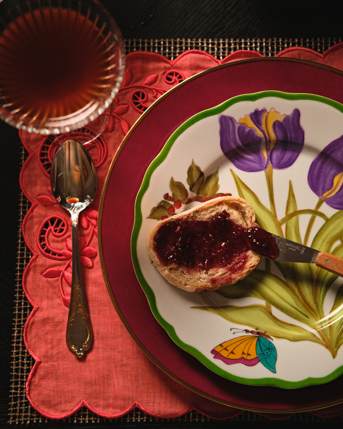 Hand-painted Solayne tulip plate with toast and jam on a red embroidered placemat